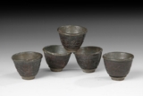 A SET OF FIVE CARVED COCONUT CUPS