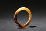 AN ARCHAIC MOTTLED JADE TWISTED-ROPE BANGLE