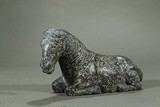 A STONE CARVING OF RECUMBENT HORSE