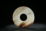 A WHITE AND RUSSET JADE CARVED 'MYTHICAL BEAST' DISC