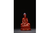 A CARVED CINNABAR LACQUER FIGURE OF BUDDHA