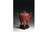 A CARVED CINNABAR LACQUER 'TAOTIE' TRIPOD CENSER AND COVER